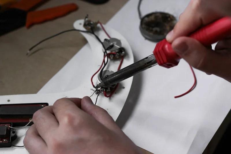 Master with a soldering iron repairs the electronics of a guitar